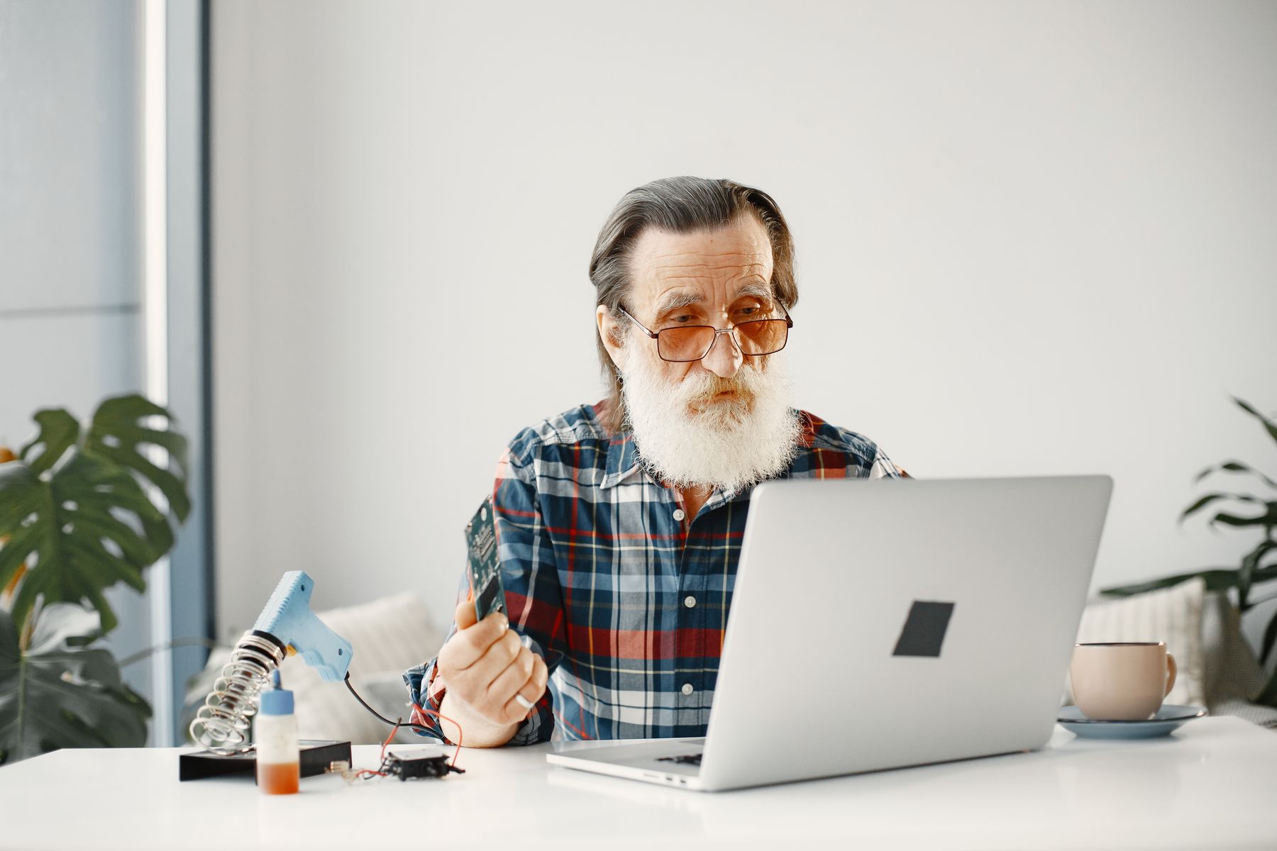 Eine Fachperson im Gespräch am Laptop, mit Werkzeug und einem Bauteil in der Hand